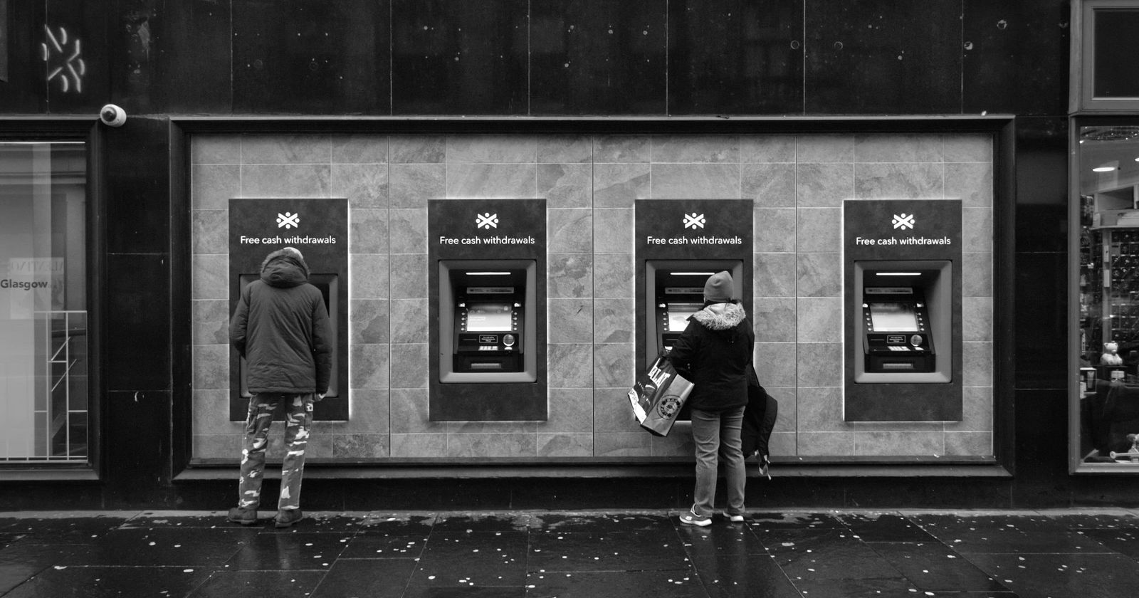 People using a row of cash machines on a city street