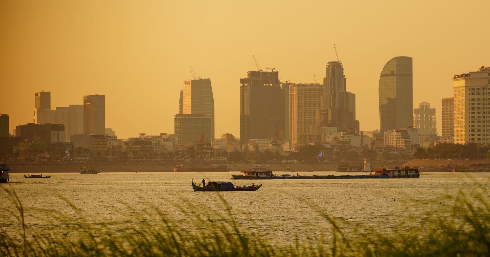Phnom Penh's skyline in hazy golden light across the river