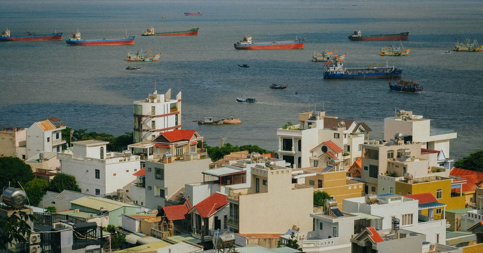 A seaside town of colourful houses, with cargo boats anchored offshore