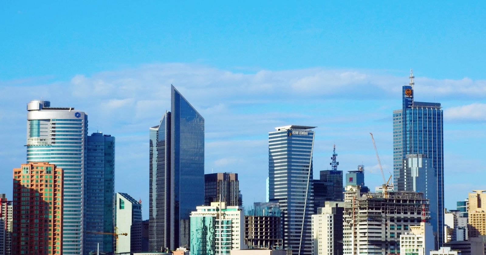 Glass office towers under a bright blue sky in a Philippine business district