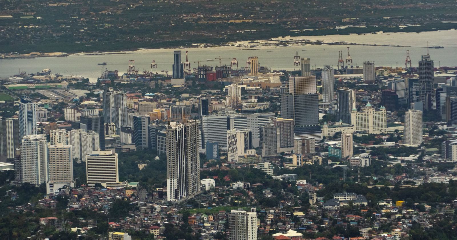 A Philippine city spreading down to the sea, seen from the hills