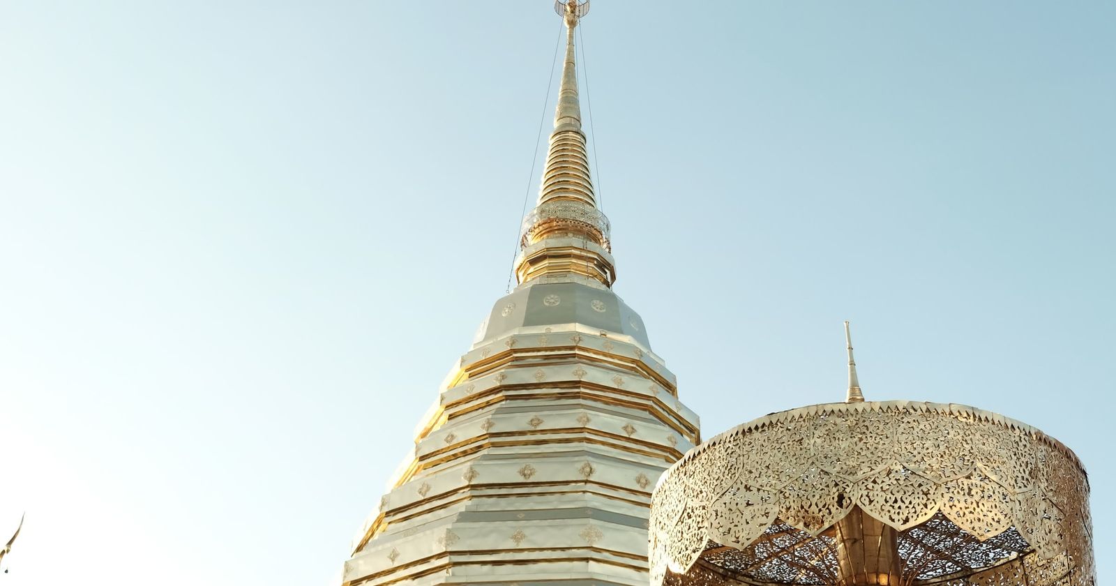 The golden chedi of a Thai temple against a pale sky